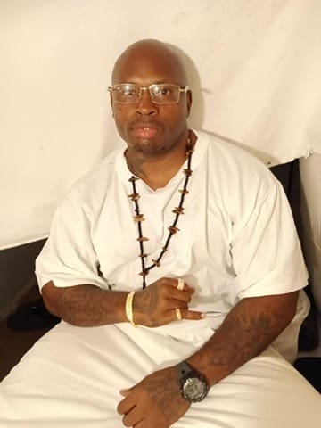 A man sitting on top of a chair wearing glasses.